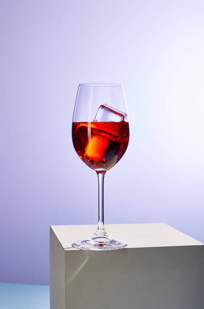 коктейль Aperol Spritz з кубиками льоду в склянці на фіолетовому фоні
  - Фото, зображення