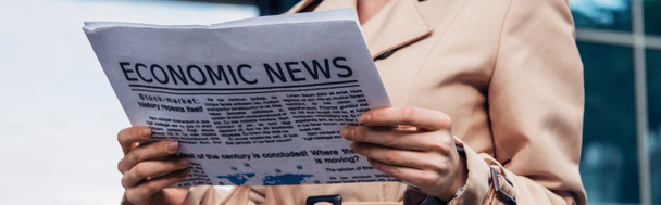panoramisch schot van vrouw in trench jas houden krant buiten  - Foto, afbeelding