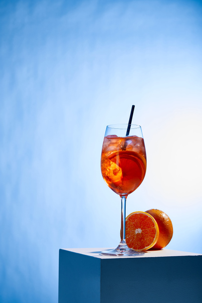 koktél Aperol Spritz szalma üveg és narancs kék alapon  - Fotó, kép