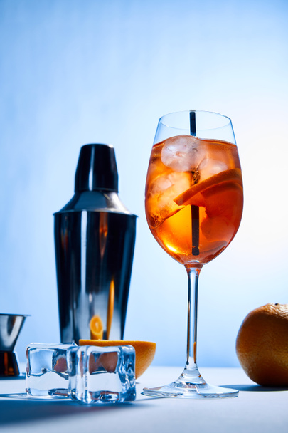 cocktail Aperol Spritz, oranges, shaker, ice cubes and measuring cup on blue background  - Foto, Imagem