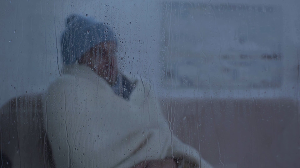 beteg ember ül ablak közelében üveg esőcseppek és tüsszentés szalvéta - Felvétel, videó