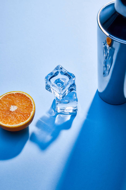 high angle view of orange, shaker, ice cubes on blue background  - Foto, afbeelding
