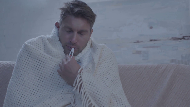 beteg ember ül asztal mellett gyógyszerekkel és a hőmérséklet mérése - Felvétel, videó
