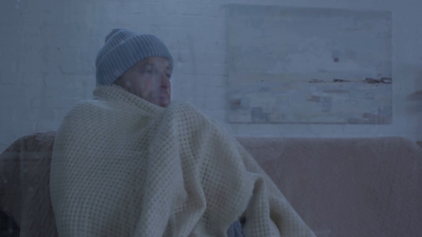 chory człowiek kichanie siedząc w pobliżu szyby okna z kroplami deszczu - Materiał filmowy, wideo