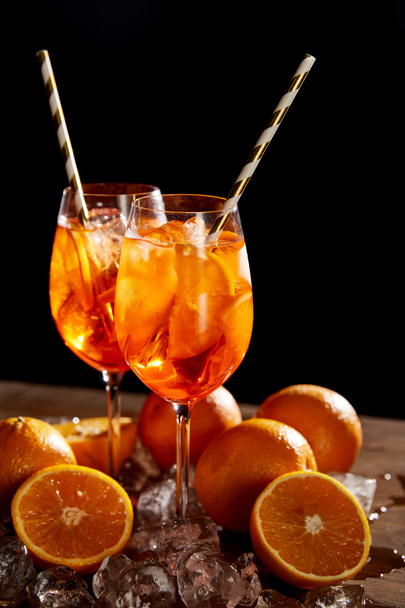 Aperol Spritz in glasses, oranges and ice cubes on black background  - Photo, Image