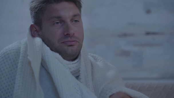 Erkrankter Mann niest, während er sich in Decke hüllt - Filmmaterial, Video