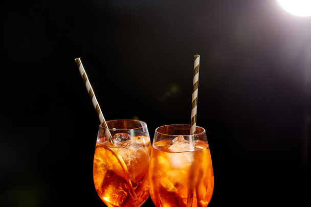 Aperol Spritz in glasses with straws on black background  - Photo, Image