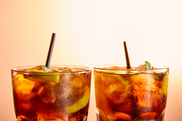 Cocktails cuba libre in Gläsern mit Strohhalmen auf beigem Hintergrund  - Foto, Bild