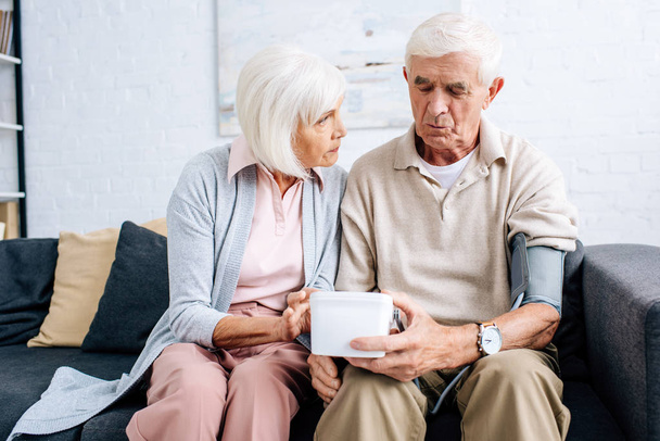 чоловік вимірює кров'яний тиск і дружина дивиться на нього в квартирі
  - Фото, зображення