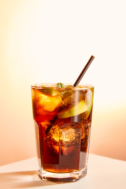cocktail cuba libre σε ποτήρι με καλαμάκι σε μπεζ φόντο  - Φωτογραφία, εικόνα