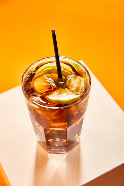 high angle view of cocktail cuba libre in glass with straw on cube  - Φωτογραφία, εικόνα