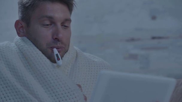 sick man measuring temperature and using digital tablet - Footage, Video