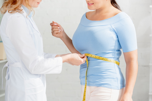 przycięty widok na ciało do pomiaru żywienia pacjenta z taśmą pomiarową w klinice  - Zdjęcie, obraz