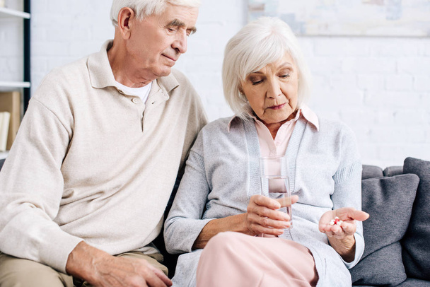 чоловік і дружина тримають таблетки і склянку води в квартирі
  - Фото, зображення