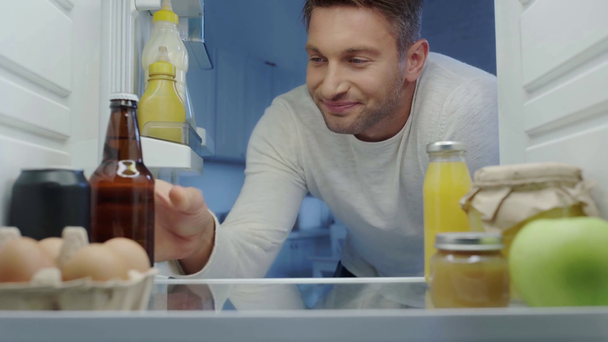 dorstige man die in de koelkast kijkt, bier neemt en de deur sluit - Video
