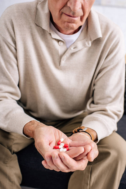 Blick auf älteren Mann mit Tabletten in Wohnung abgeschnitten  - Foto, Bild