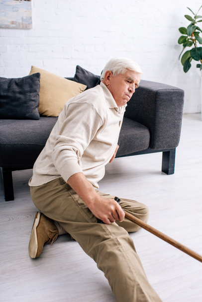 senior homme tenant canne en bois et sentir la douleur dans l'appartement
  - Photo, image