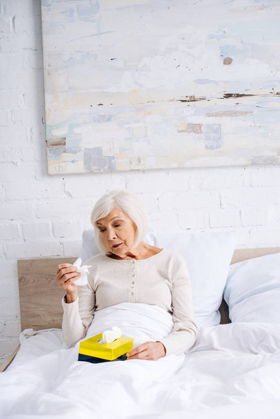 attractive and ill senior woman holding napkin in bed  - Φωτογραφία, εικόνα