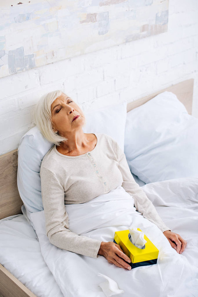 високий кут зору хворої старшої жінки з закритими очима в ліжку
  - Фото, зображення