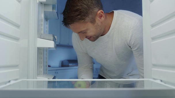 Hungriger Mann holt frischen Apfel aus leerem Kühlschrank - Filmmaterial, Video