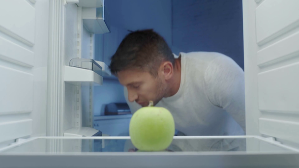 Hungriger Mann holt frischen Apfel aus leerem Kühlschrank - Filmmaterial, Video