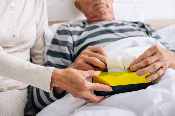 cropped view of wife giving napkins to ill husband in apartment  - Photo, Image