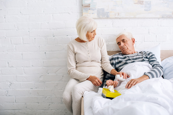 senior wife giving pills to ill husband in bed  - Photo, Image