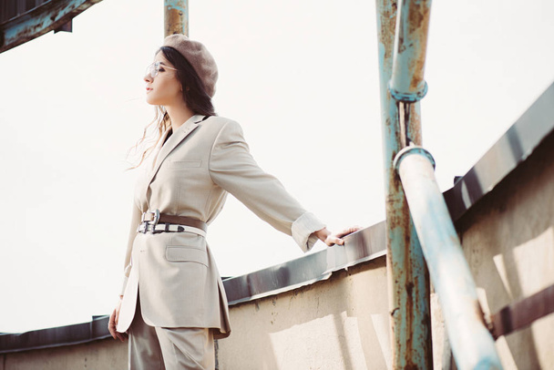 elegant fashionable woman posing in beige suit and beret on roof - Photo, Image