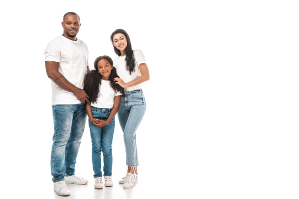 Mutlu Afro-Amerikan babası, annesi ve kızı beyaz arka planda kameraya sarılıp gülümsüyor. - Fotoğraf, Görsel