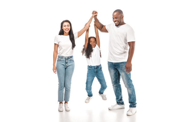 niño afroamericano alegre colgando de las manos de los padres sobre fondo blanco
 - Foto, Imagen