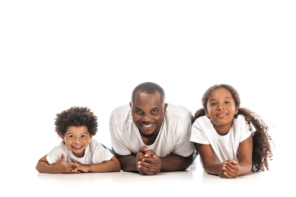 happy african american father, son and daughter smiling at camera while lying on white background - Fotografie, Obrázek