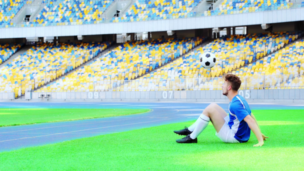 Futbolcu oturuyor ve top zıplıyor  - Video, Çekim