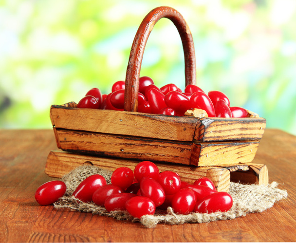Fresh cornel berries in basket on wooden table - Фото, изображение