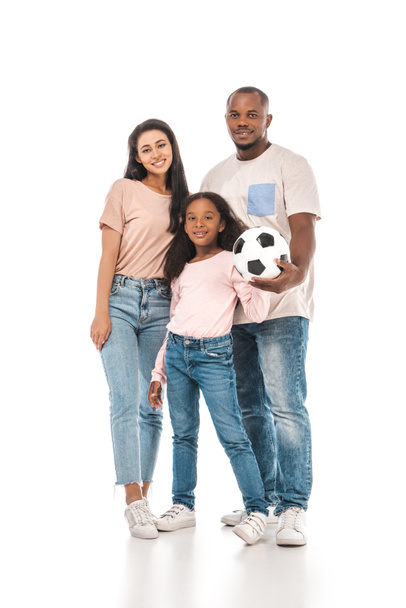 feliz afro-americano homem segurando bola de futebol perto sorrindo esposa e filha no fundo branco
 - Foto, Imagem