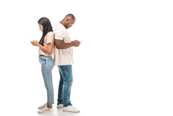 jovem casal afro-americano de pé de volta para trás e usando smartphones no fundo branco
 - Foto, Imagem