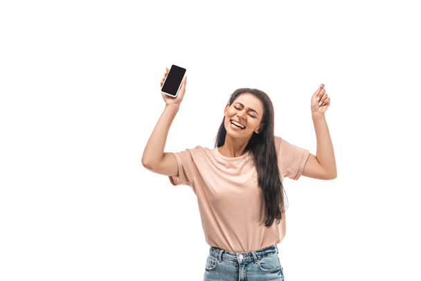 ενθουσιασμένοι Αφροαμερικανός γυναίκα κρατώντας smartphone με λευκή οθόνη και δείχνει το νικητή χειρονομία απομονώνονται σε λευκό  - Φωτογραφία, εικόνα