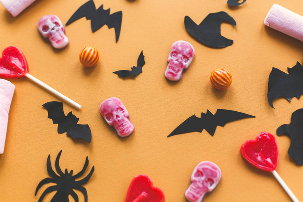 L'appartement d'Halloween. Crânes de bonbons d'Halloween avec chauves-souris noires et décorations en papier fantôme sur fond jaune. Trick or treat concept. Joyeux Halloween
 - Photo, image