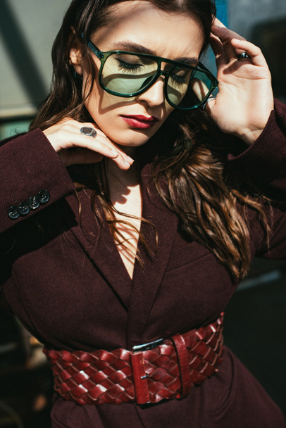 elegant girl posing in trendy burgundy suit and sunglasses on urban roof  - Photo, Image