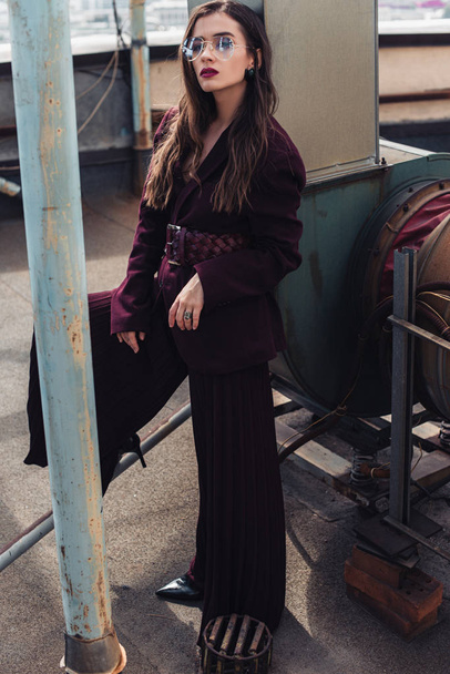 stylish elegant girl posing in trendy burgundy suit and sunglasses on urban roof  - Foto, imagen
