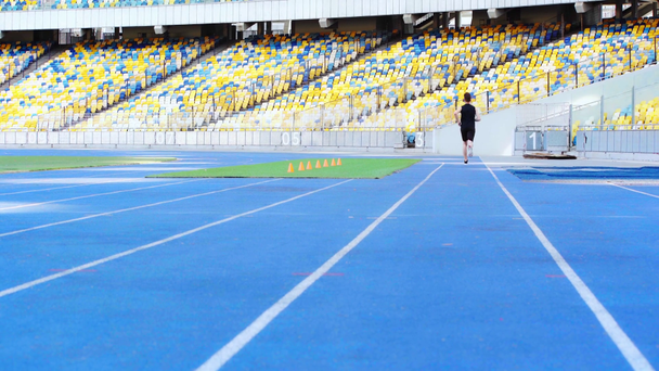 widok z tyłu biegacza biegającego na stadionie  - Materiał filmowy, wideo