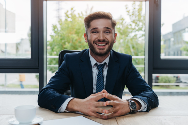 cheerful businessman smiling at camera while sitting in meeting room - Foto, immagini