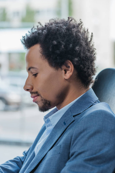 thoughtful african american businessman sitting near window in office - Photo, Image