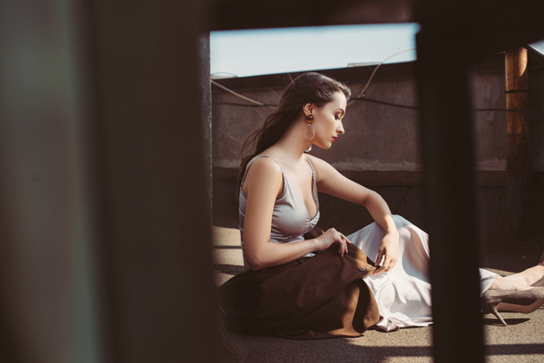 atraktivní elegantní žena pózuje v hedvábných šatech a hnědé bundy na střeše - Fotografie, Obrázek