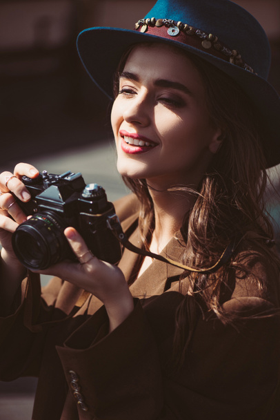 mujer sonriente en sombrero tomando fotos en la cámara de fotos vintage en el techo
 - Foto, Imagen