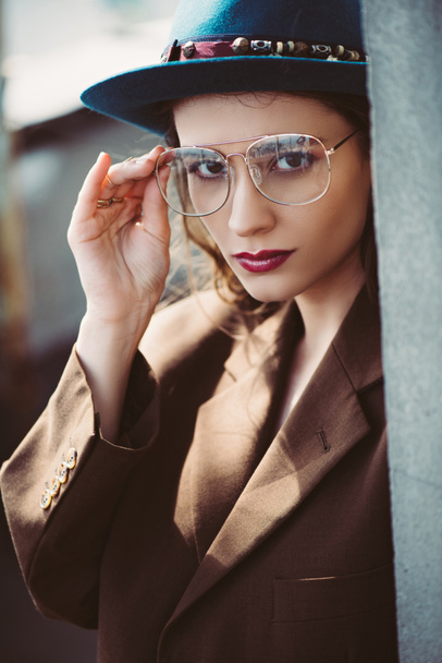 fashionable elegant woman posing in hat, eyeglasses and brown jacket on roof - Foto, immagini