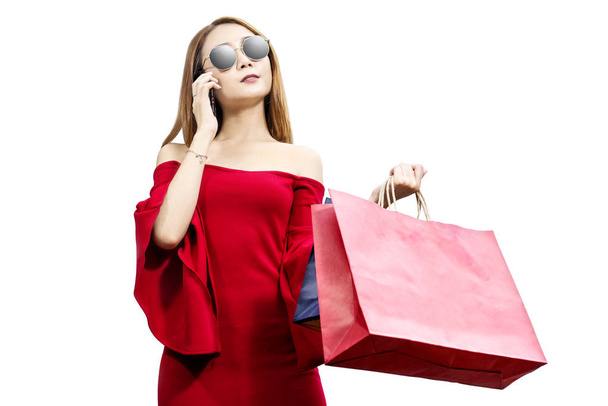 Donna asiatica in abiti rossi e occhiali da sole utilizzando il telefono cellulare
 - Foto, immagini