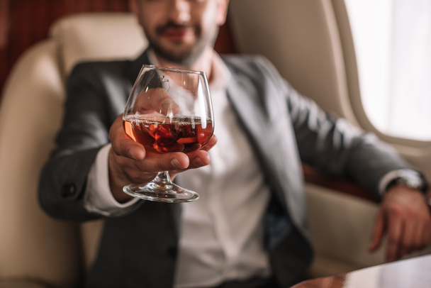 selective focus of glass with cognac in hand on businessman  - Photo, Image
