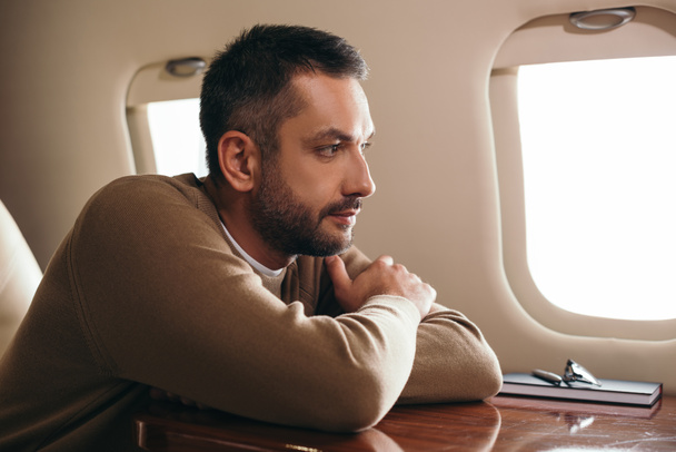 jóképű szakállas férfi ül az első osztályú magánrepülőn  - Fotó, kép
