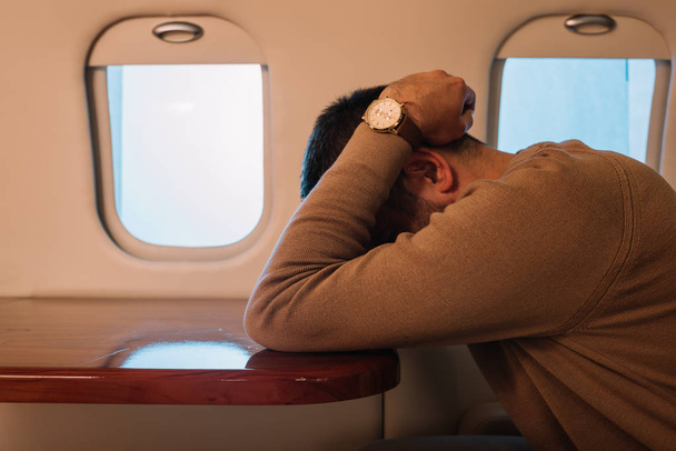 uomo spaventato con mal d'aria volto di copertura in jet privato
  - Foto, immagini