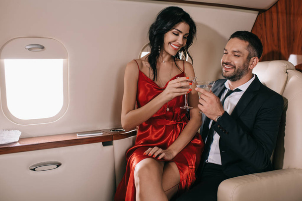 feliz pareja sosteniendo vasos de martini en jet privado
  - Foto, imagen